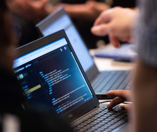 close up of people coding on laptops
