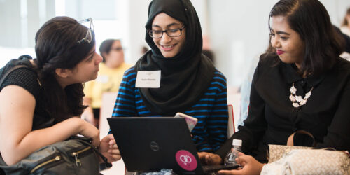 Three students working on a computer and talking together
