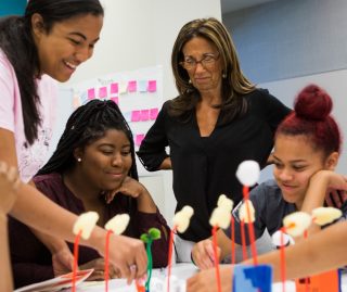 Students working on a project as Judy watches