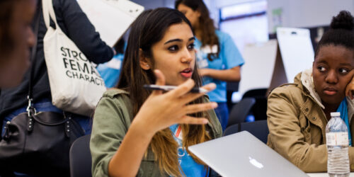In the News Hero Image - Seated young woman speaking to others
