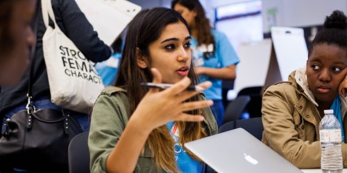 In the News Hero Image - Seated young woman speaking to others