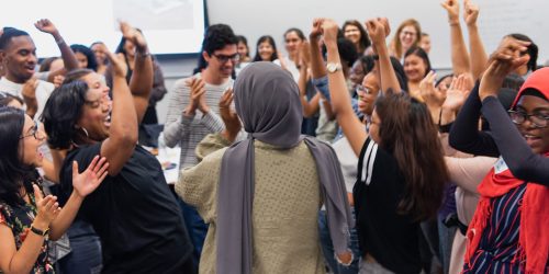 group of students with arms in the air cheering and smiling