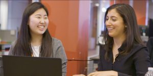 two women smiling at a computer