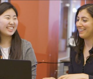 two women smiling at a computer