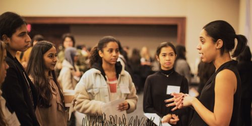 students talk to a corporate representative at a networking event